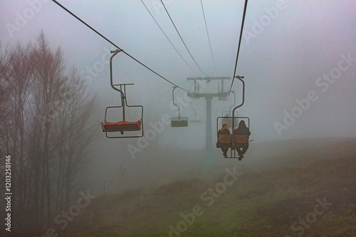 Obraz na płótnie Silent journey through the misty mountains at dusk with empty and occupied lifts w salonie