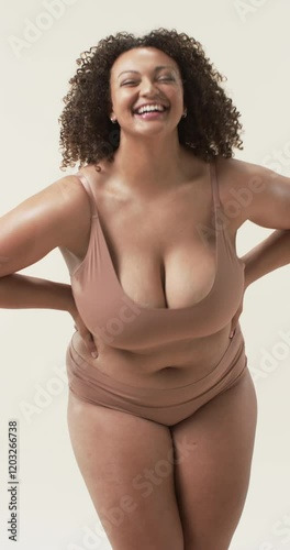 Vertical video: Smiling plus size woman in underwear posing confidently, embracing body positivity