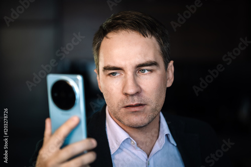 a man reads a questionable message with disbelief on his face. Portrait of brunette man in t-shirt using cellphone, reading news message, mobile application. A suspicious look