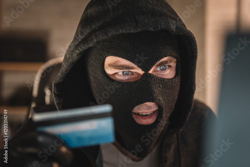 Photography male thief holds a credit card in his hand and picks up a password to steal money