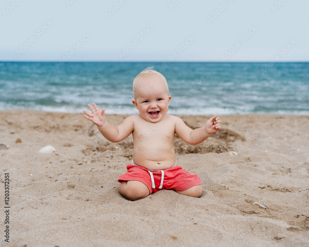 Smiling baby crawling and playing on seaside. Happy little child playing on beach near ocean. Smiling baby crawling and playing on seaside. Happy little child playing on beach near ocean.