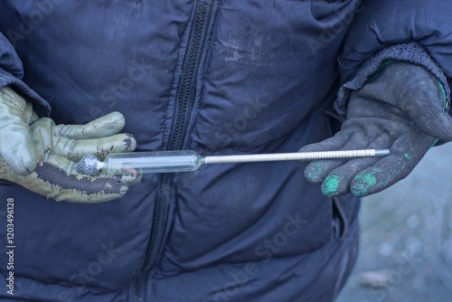 fingers holding an one old glass alcohol thermometer on an autumn street