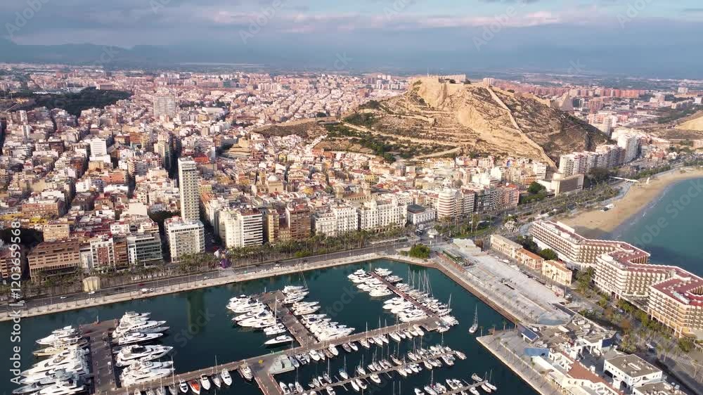 Cinematic aerial view of Alicante city. Famous travel destination in Spain. View of Castle of Santa Bárbara on top of the hill. Sunset point with orange and pink reflections. Promenade of Alicante.