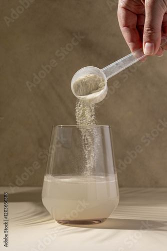 Protein powder added with measuring scoop in a glass of water. Nutrition and food supplement photo
