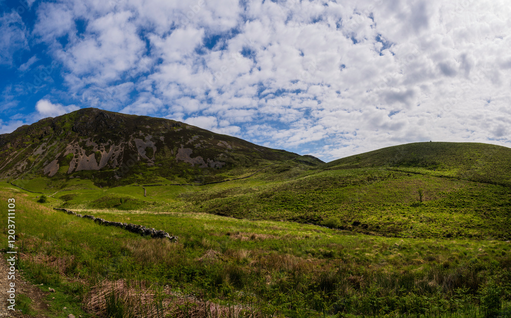 Fototapeta premium Serene Hills and Verdant Landscapes Near the Start of Minffordd Path to Penygader (Cadair Idris) Under a Sky of Billowing Clouds