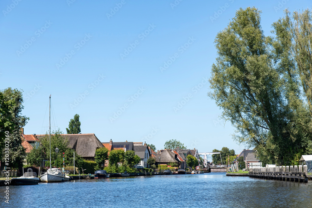 Obraz premium Panoramic view over the water of Ossenzijlersloot in Ossenzijl, the Netherlands near National Park Weerribben a fen or swapland with peatlands and reed beds