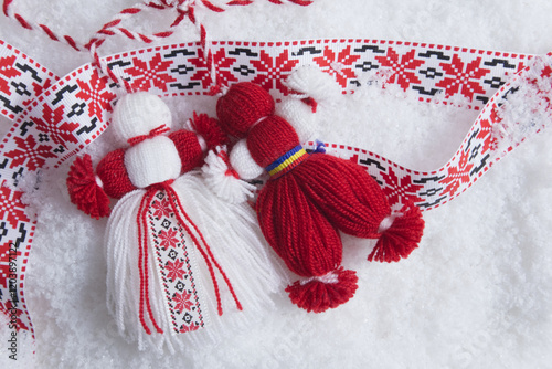 Martenitsa, Martisor, in snow with ribbon with folk ornament with copy space
