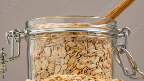 Close-up of rolled oats stored in a glass jar with a wooden spoon, representing sustainable and healthy food storage. photo