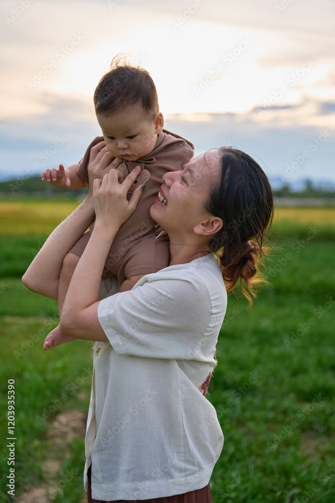 there is a woman holding a baby in her arms in a field there is a woman holding a baby in her arms in a field