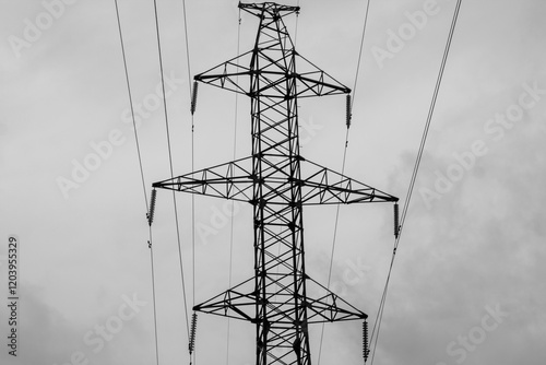 High-voltage power lines against the cloudy sky. Black and white photo.