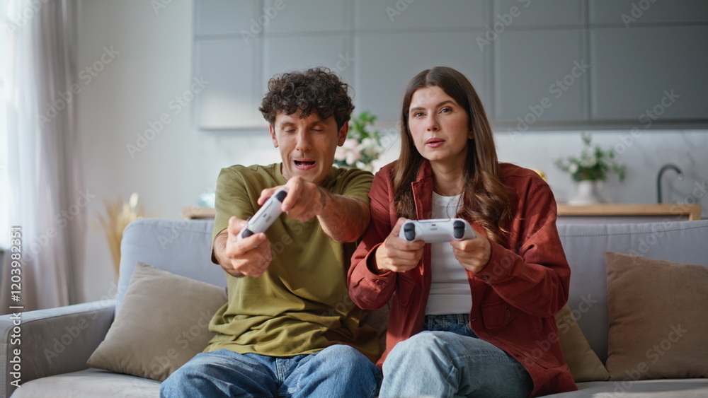 Married pair pressing console buttons playing online video game at home sofa Married pair pressing console buttons playing online video game at home sofa