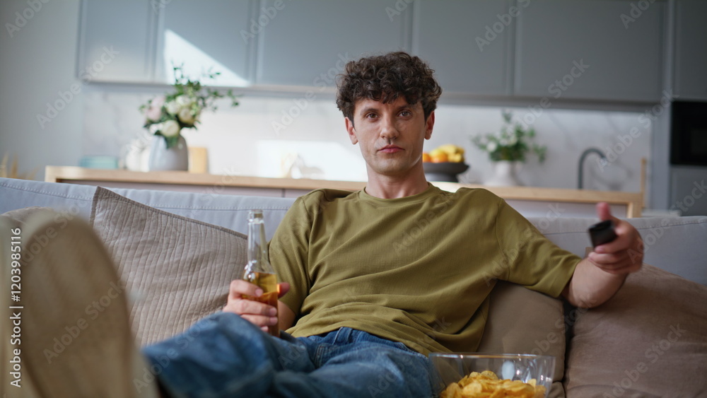 Curly hipster switching channels on tv with remote controller at couch closeup Curly hipster switching channels on tv with remote controller at couch closeup