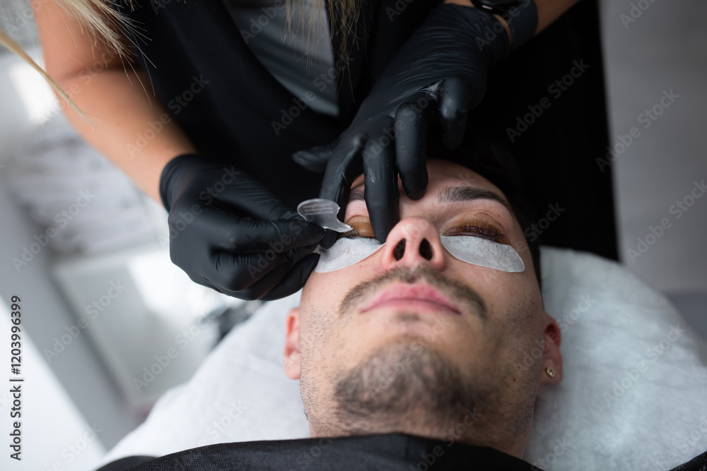 Fototapeta premium A young guy in a beauty salon, the concept of eyelash care
