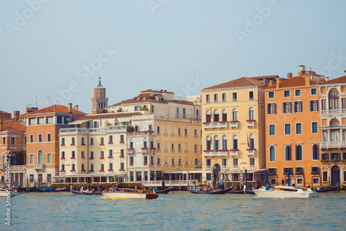 A picturesque view of Venice's vibrant waterfront showcasing historic colorful buildings, gondolas, and water taxis along the canal. Perfect for travel, culture, and urban photography themes.  photo