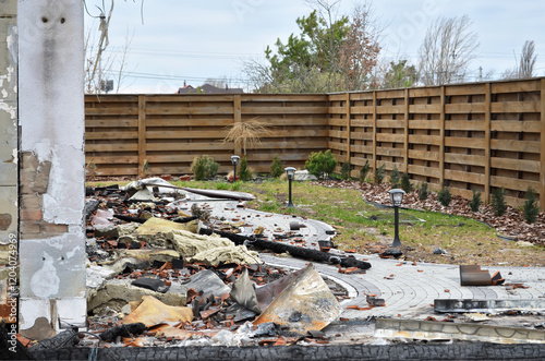 Damage from a devastating fire that destroyed a private home. Charred, burnt remains of a fire-damaged building with debris scattered in the courtyard. photo