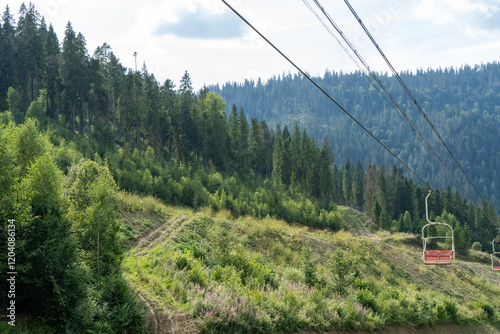 Ski lift in green forest. Cableway in Mountains. Summer nature outdoor trees photo