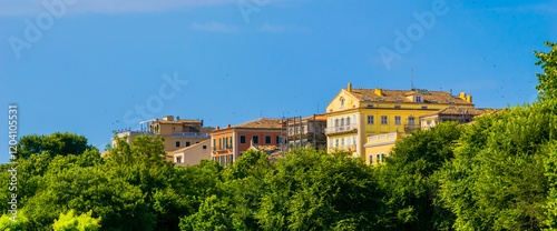 Panoramic view of old colorful Venetian building rooftops peaking over lush green trees on Spianada Square, Corfu island, Greece photo