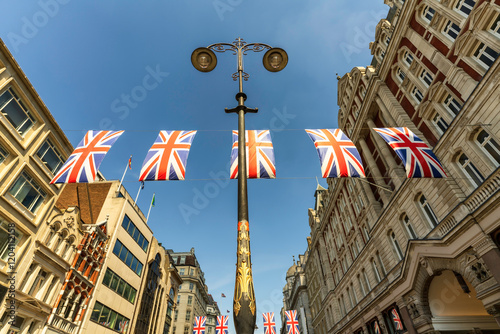 Canvas Print Several UK Union Jack flags bunting, flying over Strand street in the London city center, the theatre district with English buildings