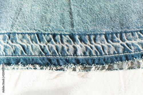 Close-up of distressed denim fabric.  The frayed edges and textured weave showcase the garment's worn look.