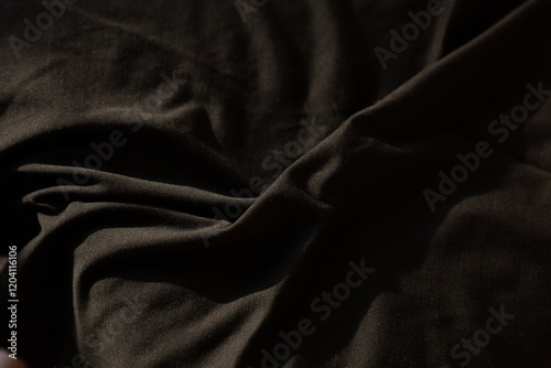 Close-up of dark fabric texture. Soft, draped material with subtle folds and shadows.  Perfect for background or textile design.