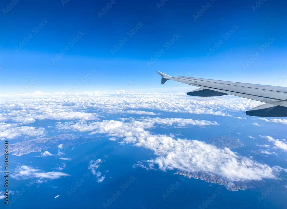 Plane flying over clouds, view from airplane window, fluffy cloudscape and blue sky Plane flying over clouds, view from airplane window, fluffy cloudscape and blue sky