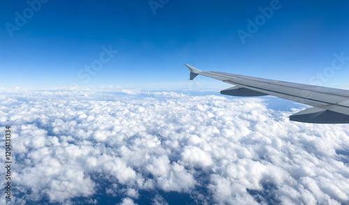 Plane flying over clouds, view from airplane window, fluffy cloudscape and blue sky photo