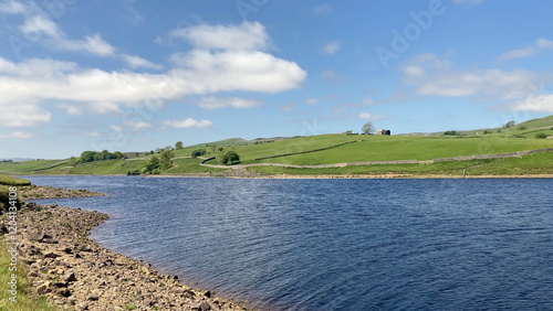 Tranquil view of Grassholme Reservoir surrounded by rolling hills and open fields beneath a bright sky - County Durham, UK photo