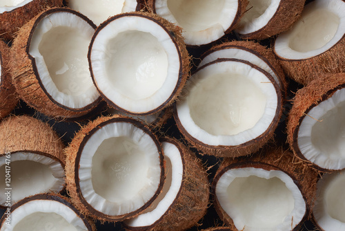 pile of coconuts cut in half in close-up view, brown fibrous husk and inner white flesh visible, abundance and freshness concept