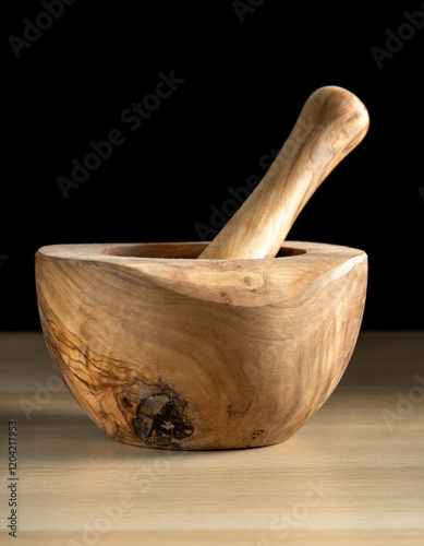 Wooden mortar and pestle resting on a wooden table.