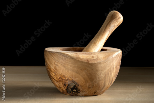 Wooden mortar and pestle resting on a wooden table.