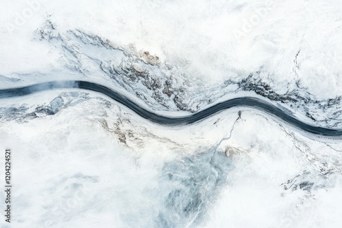 Aerial view of a winding river snaking through a snow-covered, mountainous landscape.