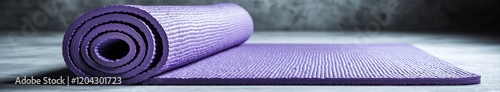 Rolled purple yoga mat on concrete surface in minimalist setting