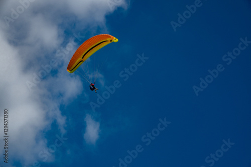 Fototapeta Naklejka Na Ścianę i Meble -  Paraglider flight against a blue sky with clouds. Beskidy Mountains, Poland