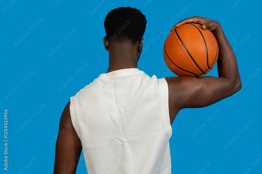 Basketball player holding ball on shoulder, rear view on blue background Basketball player holding ball on shoulder, rear view on blue background