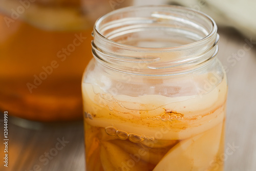 Homemade black tea kombucha or tea mushroom in glass jar with lots of scoby, a healthy fermented probiotic drink (Selective Focus, Focus on the front of the top scoby) photo