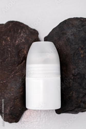 White cylindrical container placed between two dark stones on a light surface for product display and branding photo