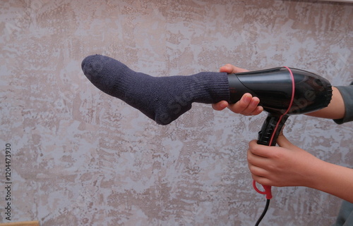 A person dries a sock with a hairdryer.