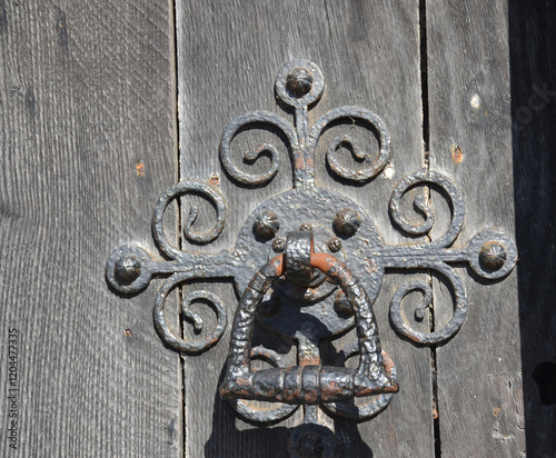 Old iron ornate door knocker on a wooden door of the Salisbury Cathedral, Salisbury, Wiltshire, England, UK.