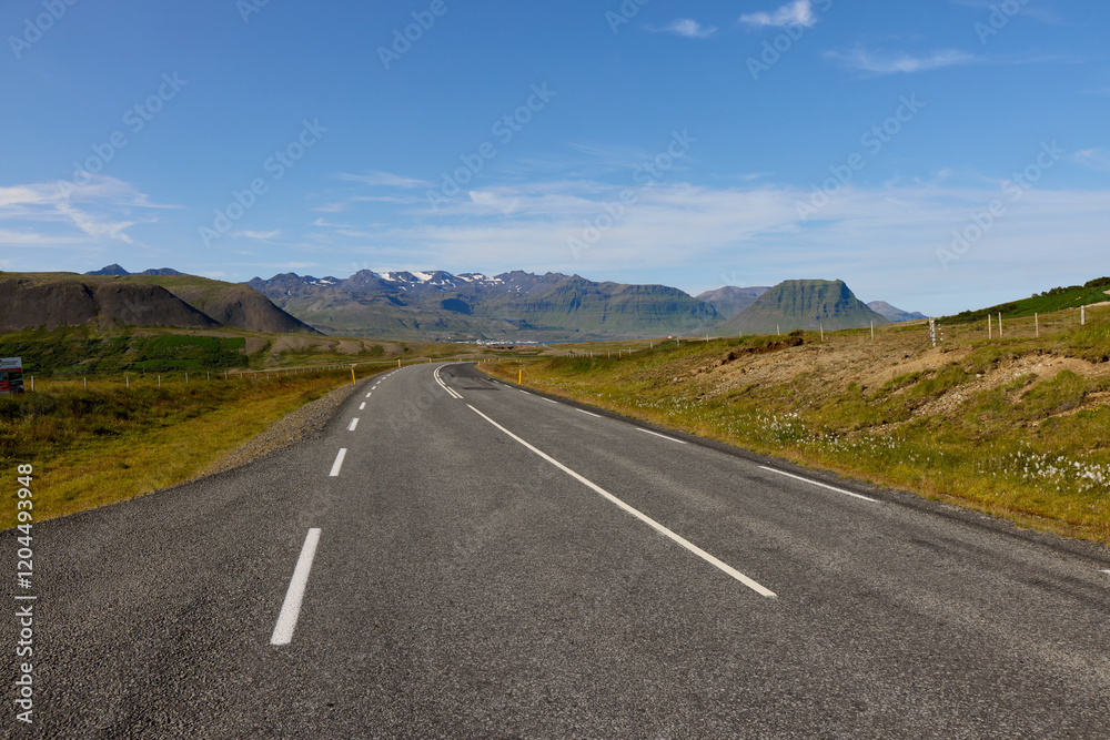 Empty highway through Icelandic mountain landscape. Road with white markings leading to distant peaks. Transportation infrastructure, travel, and scenic drive concept Empty highway through Icelandic mountain landscape. Road with white markings leading to distant peaks. Transportation infrastructure, travel, and scenic drive concept