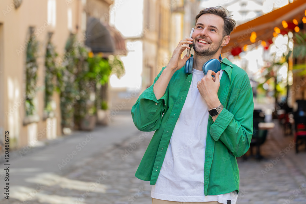 Fototapeta premium Caucasian man tourist having remote conversation communicate speaking by smartphone with friend, talking on phone unexpected good news gossip standing on urban city street. Town lifestyles outdoors.