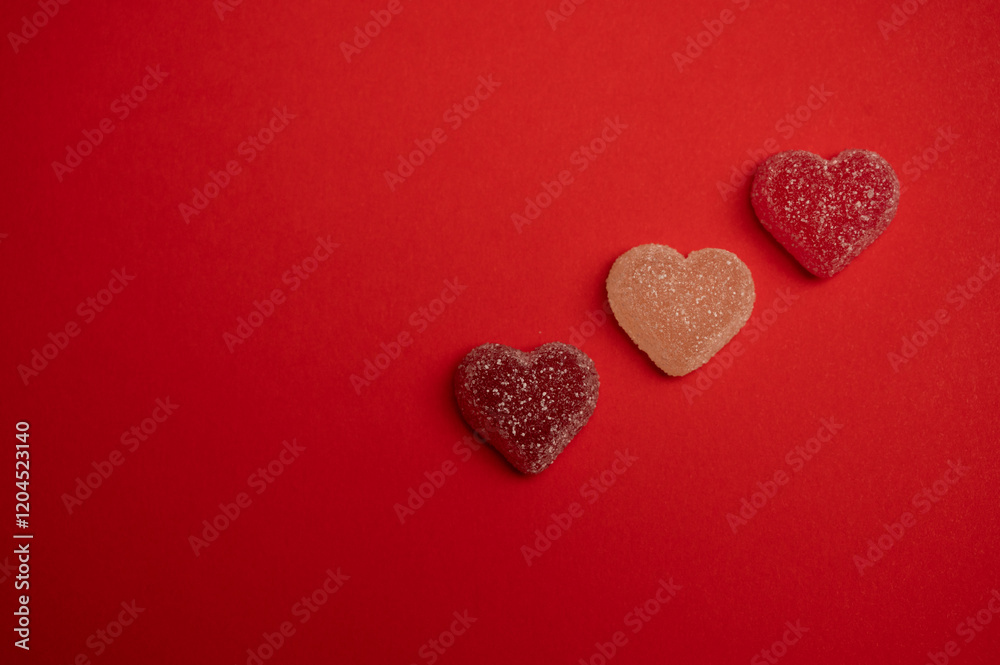 Obraz premium Heart-shaped gummy candies on a vibrant red background, symbolizing love and romance. Perfect for Valentine's Day themes, holiday promotions, greeting cards, and romantic celebrations