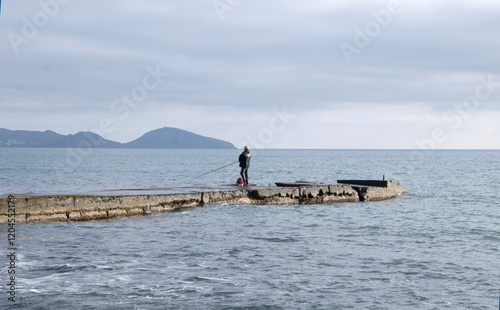 Seascape with a fisherman standing on a pier.