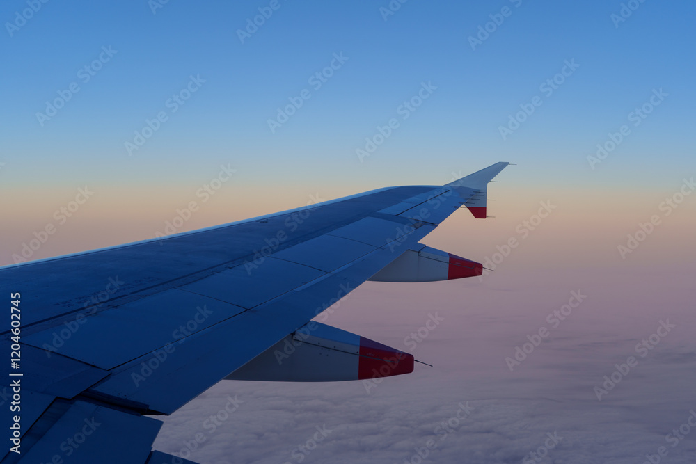 Fototapeta premium An airplane wing against a colorful sunrise sky.