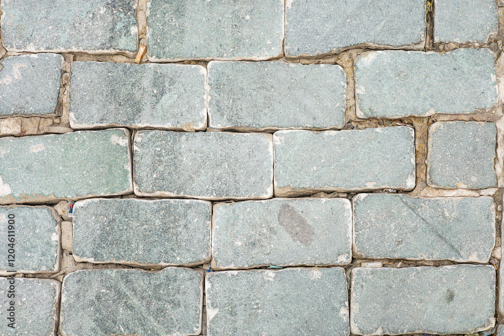 Naklejka premium Close-up view of weathered stone pavement with rectangular slabs in earthy tones