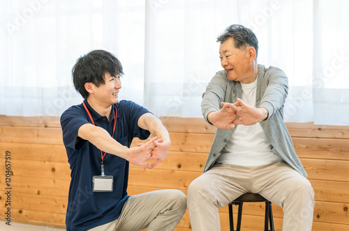リハビリで体操をする車椅子に乗ったシニア男性と理学療法士・作業療法士の男女スタッフ
