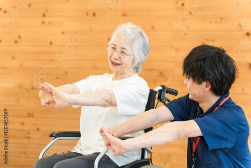 リハビリで体操をする車椅子に乗ったシニア女性と理学療法士・作業療法士の男性スタッフ
