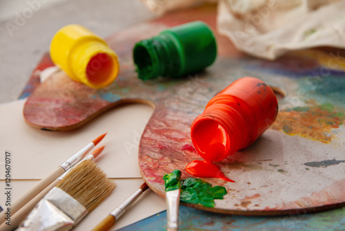Acrylic paints red lies open on palette and green paint next to brushes