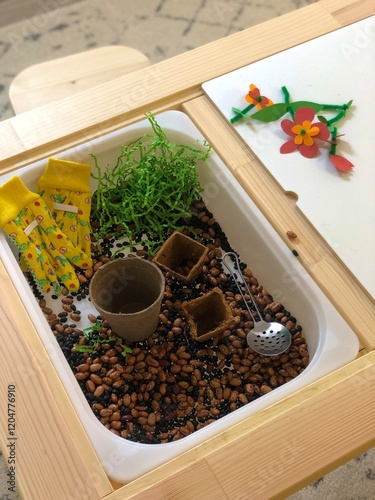 A sensory table displaying garden and spring themed activities with items like seeds, pots, and play tools showcasing educational, creative, and imaginative hands on play for children indoors.