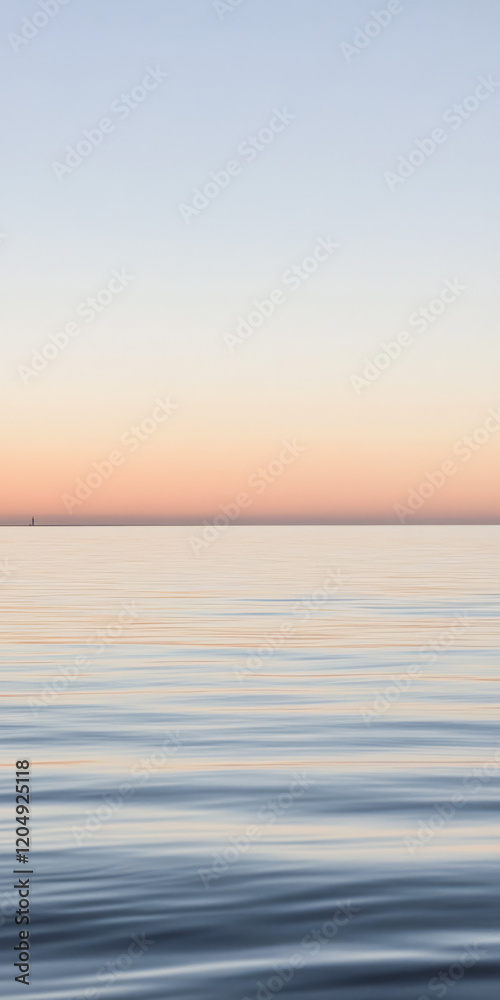 Obraz premium Calm ocean at sunset with soft pastel colors reflecting on the water