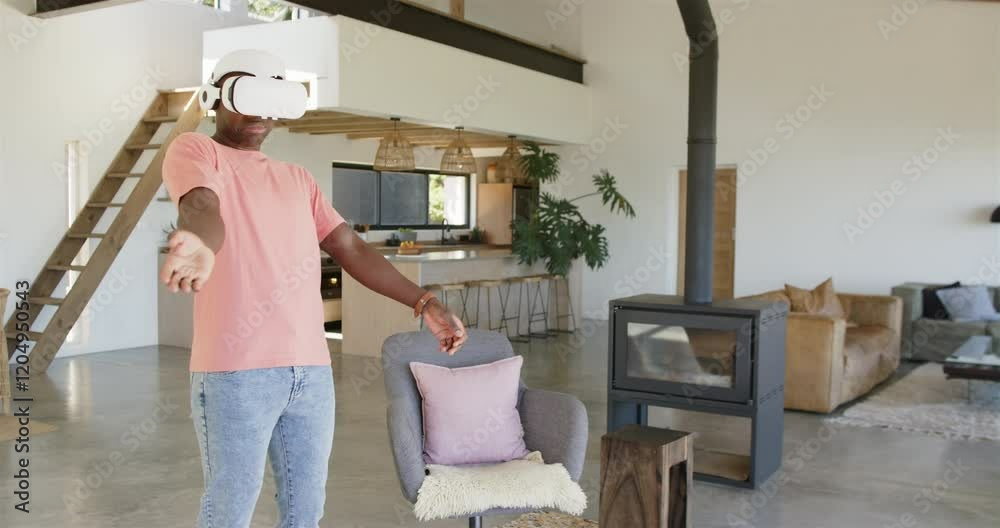 Using VR headset, man enjoying virtual reality experience in modern living room, copy space Using VR headset, man enjoying virtual reality experience in modern living room, copy space